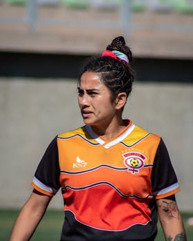 Female soccer player wearing a colorful jersey during a sunny day at a football field in Chile.