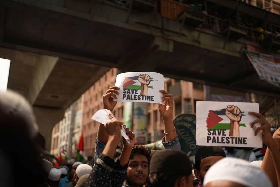 Crowd holding 'Save Palestine' signs at a protest in Dhaka, Bangladesh.