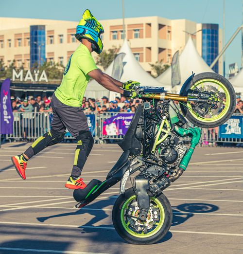Free Stunt rider performs thrilling motorcycle trick at an outdoor event in Oran, Algeria. Stock Photo