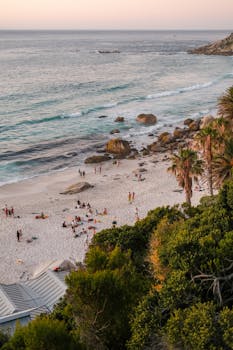 Aerial view of a vibrant beach in Cape Town, South Africa during sunset with people enjoying the shore.
