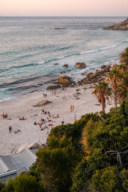 Aerial view of a vibrant beach in Cape Town, South Africa during sunset with people enjoying the shore.