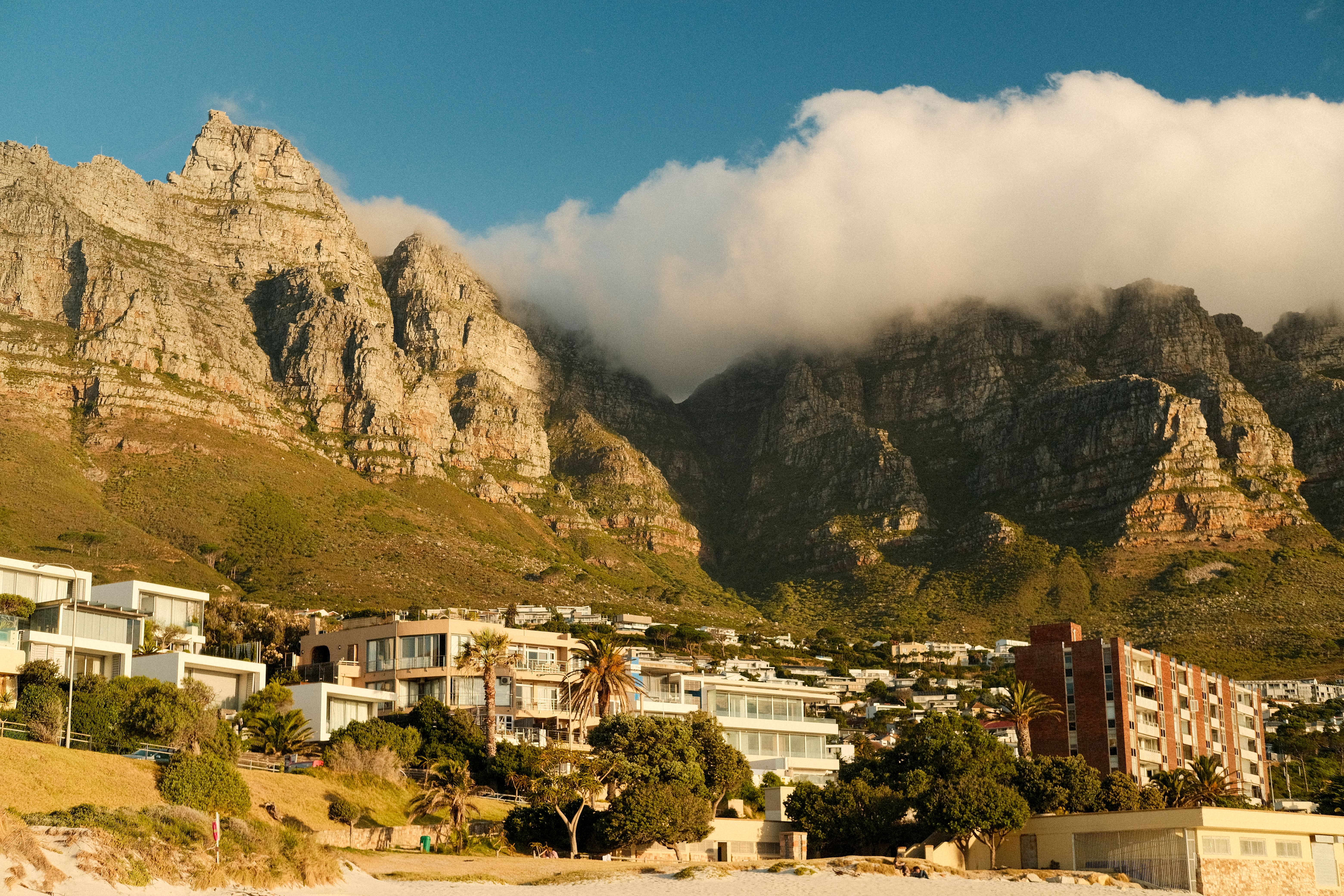 Capture of the iconic Twelve Apostles with clouds and coastal buildings in Cape Town, South Africa.