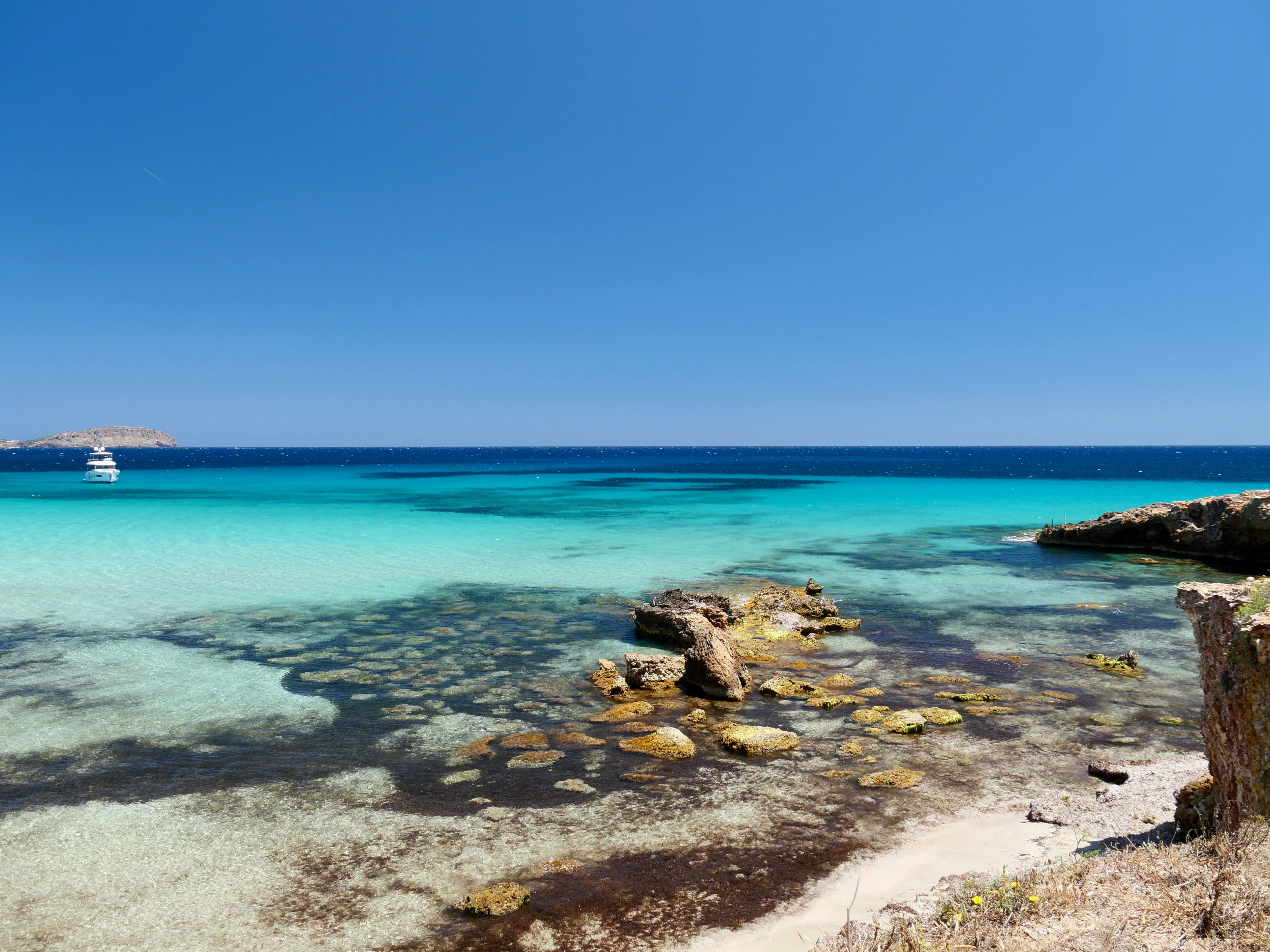A breathtaking view of Ibiza's turquoise waters and rocky coastline under a clear blue sky. - Photo by Dirk Pothen on Pexels