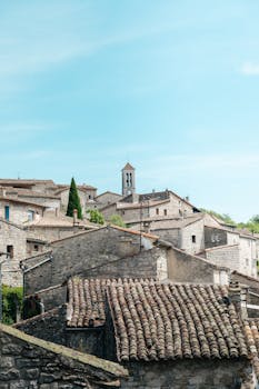 Discover the rustic charm of a traditional stone village under a blue sky in Auvergne-Rhône-Alpes, France.