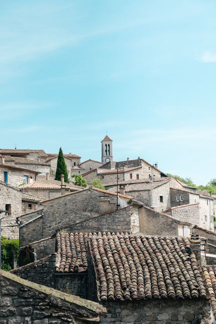 Discover the rustic charm of a traditional stone village under a blue sky in Auvergne-Rhône-Alpes, France.