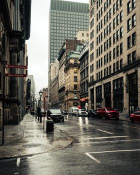 Moody downtown Montréal street with historical and modern buildings on a rainy day.