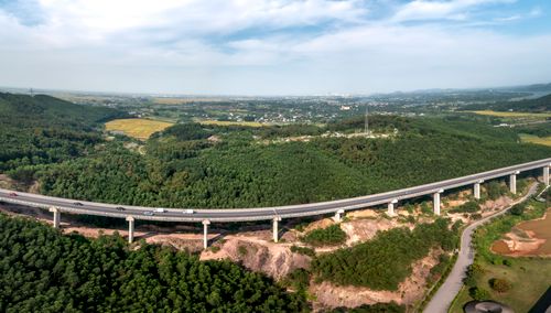 Free Aerial view of a highway curving through lush green hills under a blue sky. Stock Photo