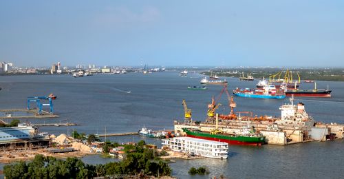 Free Aerial view of a busy harbor with cargo ships and industrial cranes under a clear blue sky. Stock Photo