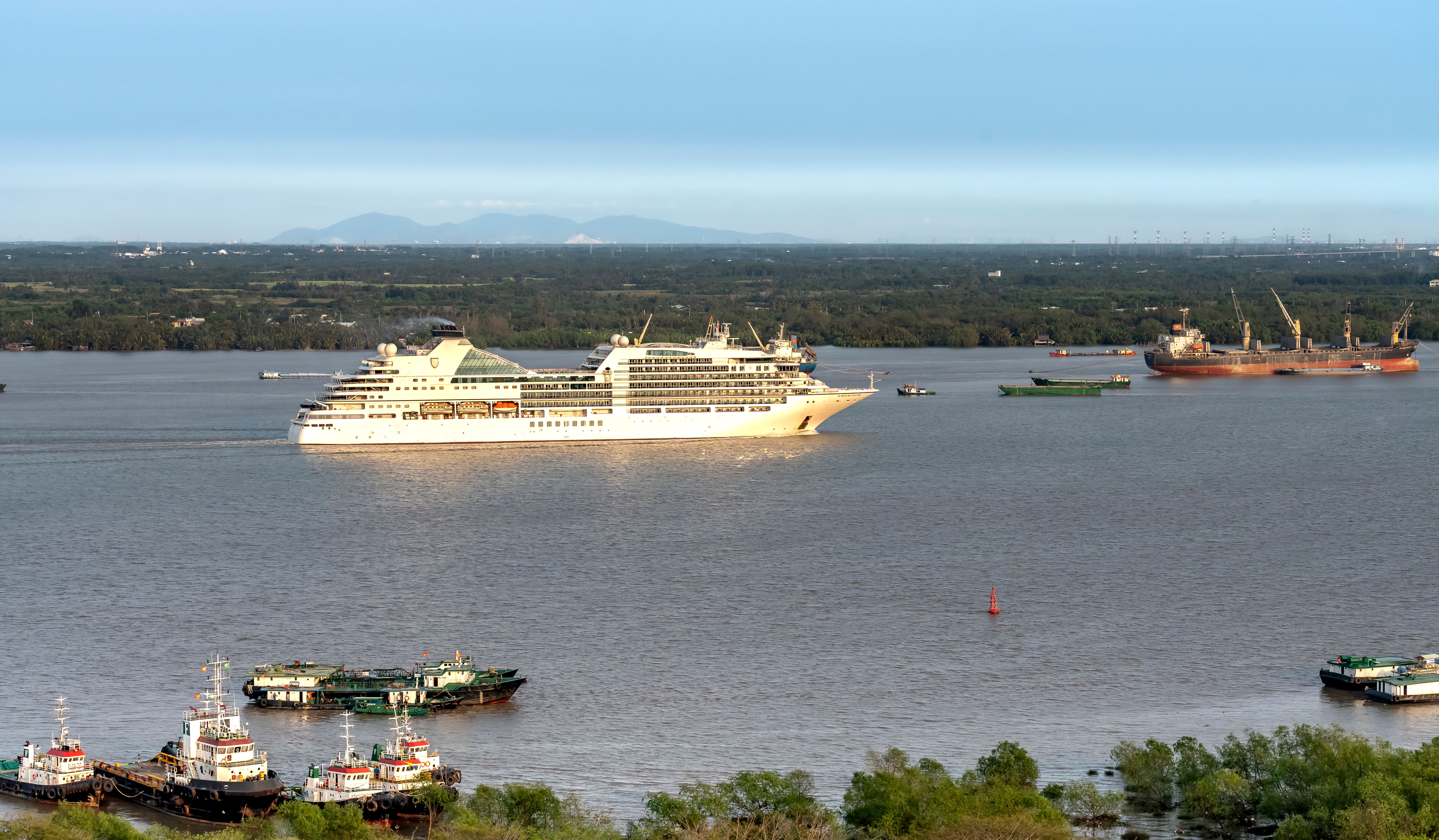 A majestic cruise ship sailing through a peaceful river with scenic views, perfect for travel inspiration.