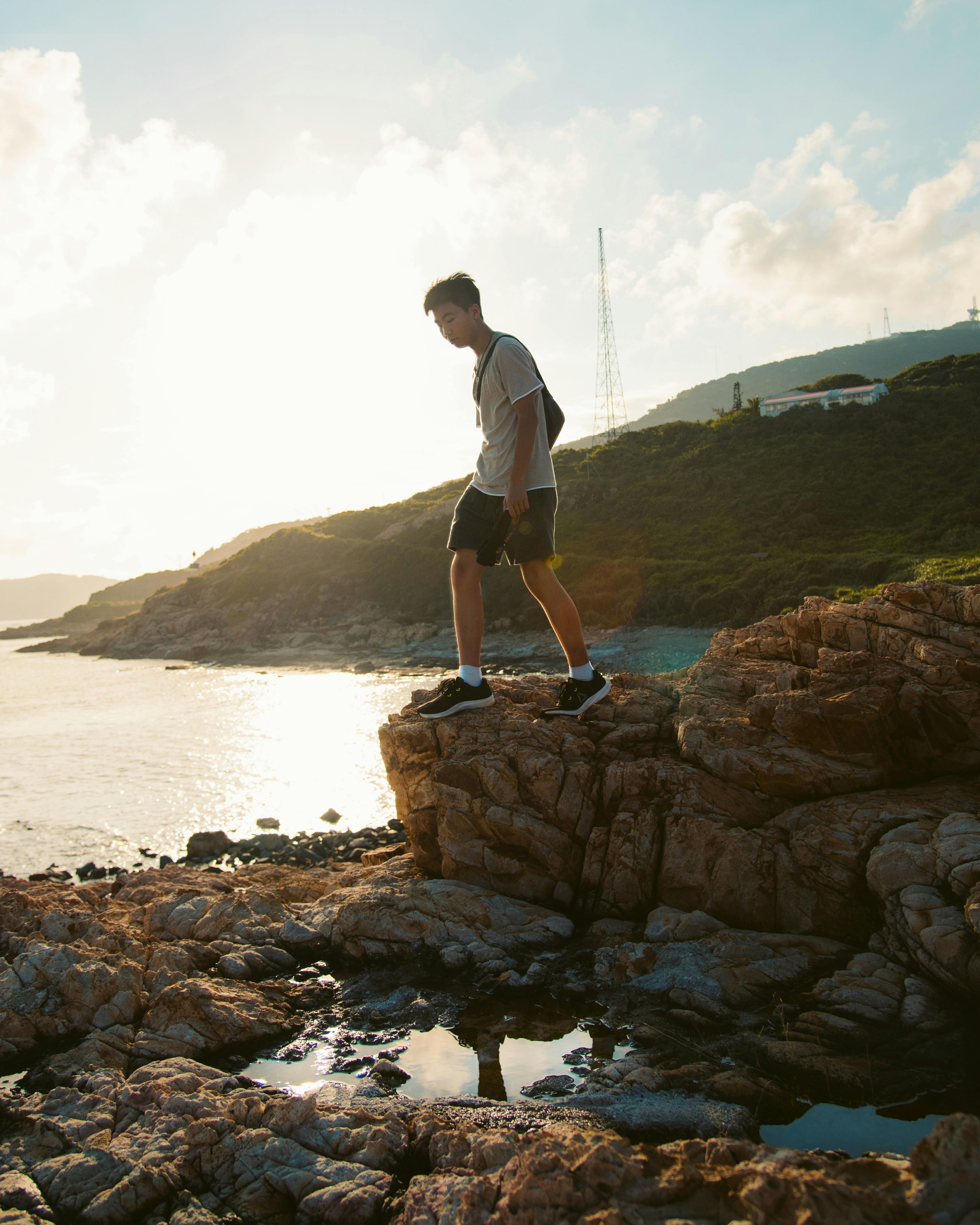 一名男子在美丽的香港日落中，探索岩石海岸线，捕捉到冒险与宁静交织的时刻