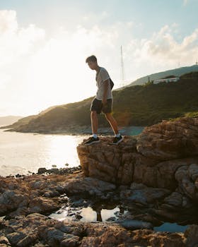 一名男子在美丽的香港日落中，探索岩石海岸线，捕捉到冒险与宁静交织的时刻