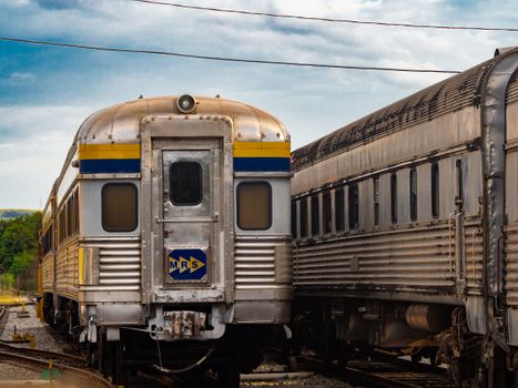 A classic train carriage parked in a railway yard under a cloudy sky.