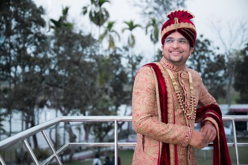 Free A smiling groom in luxurious traditional attire poses outdoors with a natural background. Stock Photo