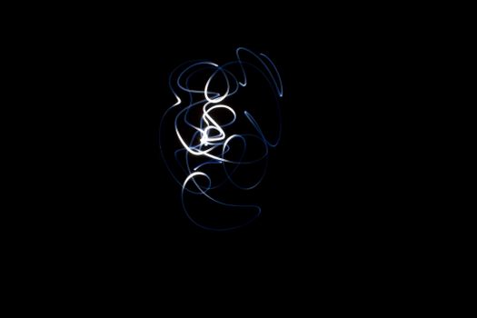 Swirling white light trails create abstract designs against a black background.