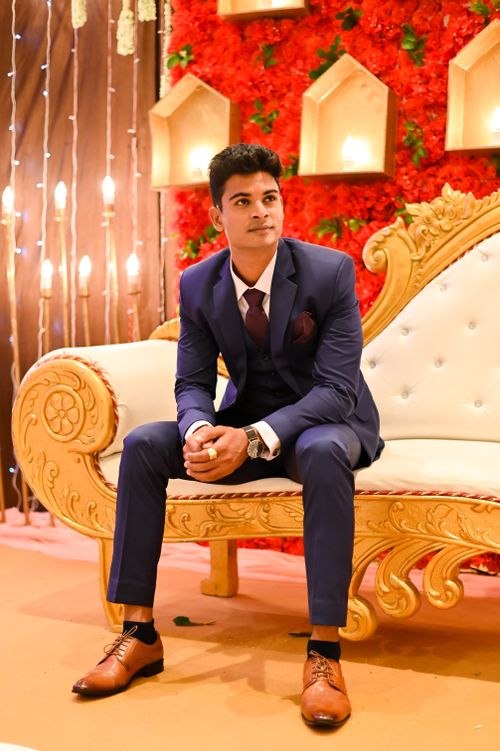 Free Stylish groom in blue suit seated in lavish wedding setting, exuding elegance. Stock Photo