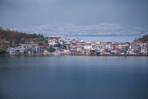 Free Picturesque lakeside town with serene water and mountains in the background. Stock Photo