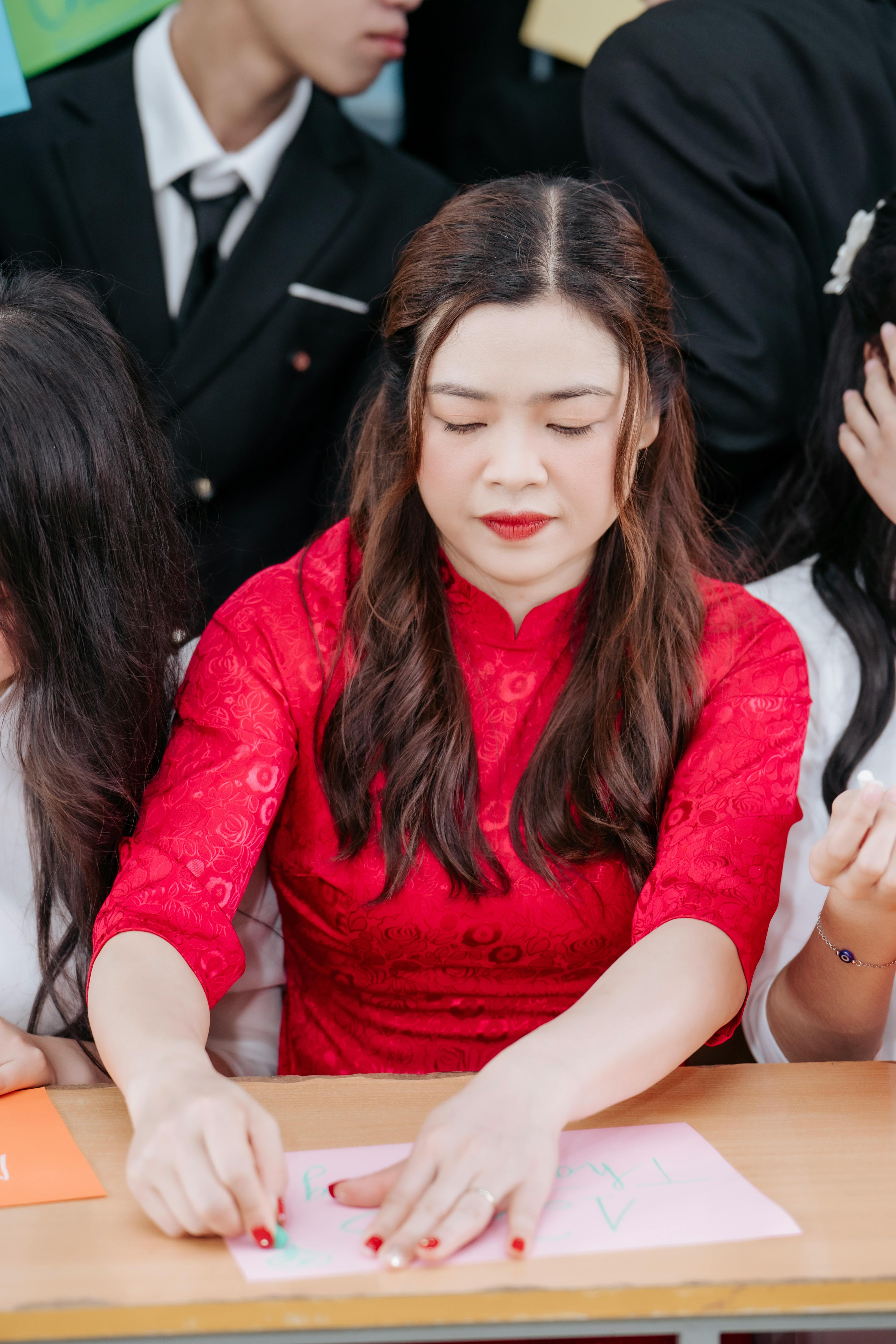 Free Woman wearing a red traditional dress working on arts and crafts at a table. Stock Photo
