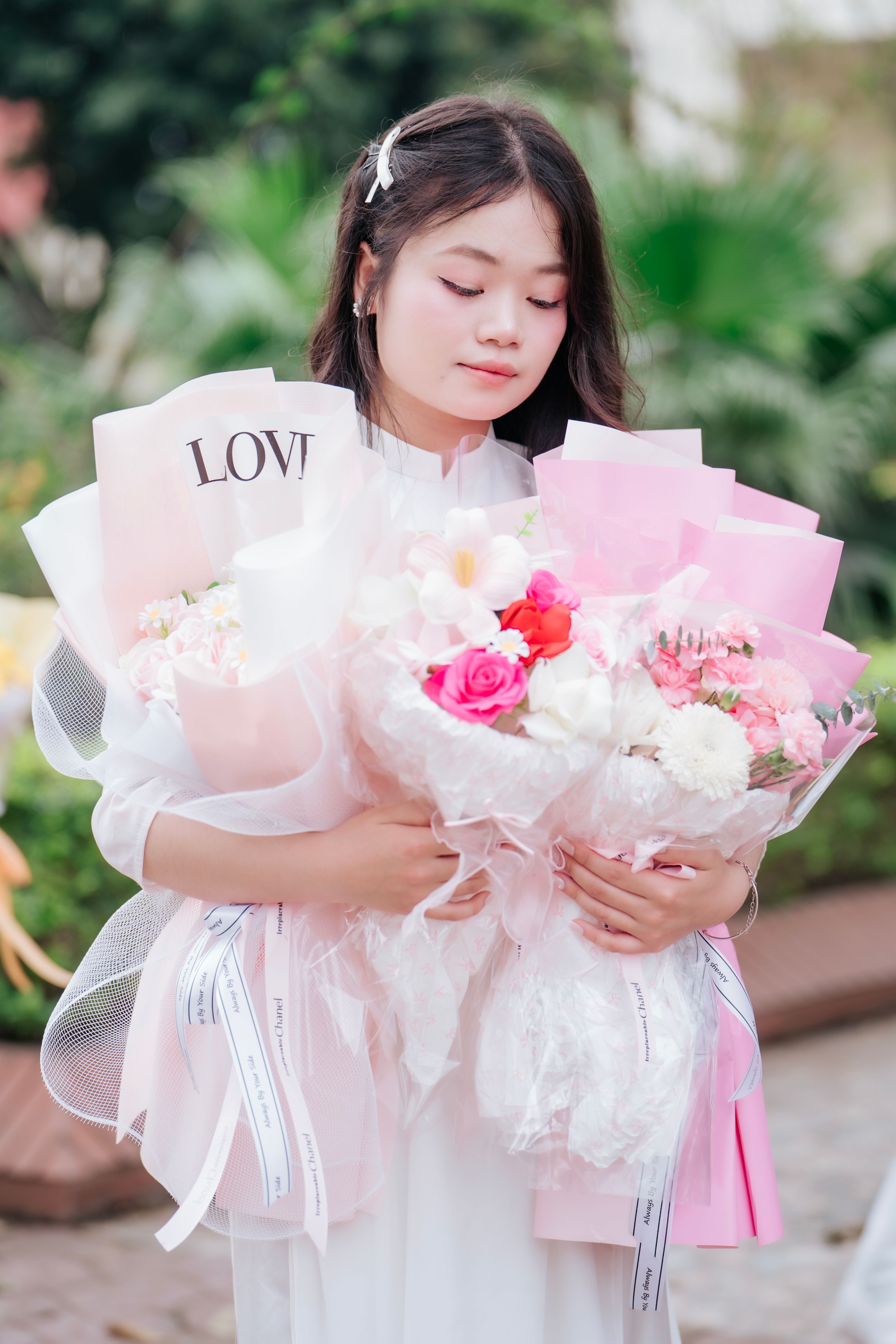 Young Woman Holding Bouquets of Pink Flowers Outdoors · Free Stock Photo