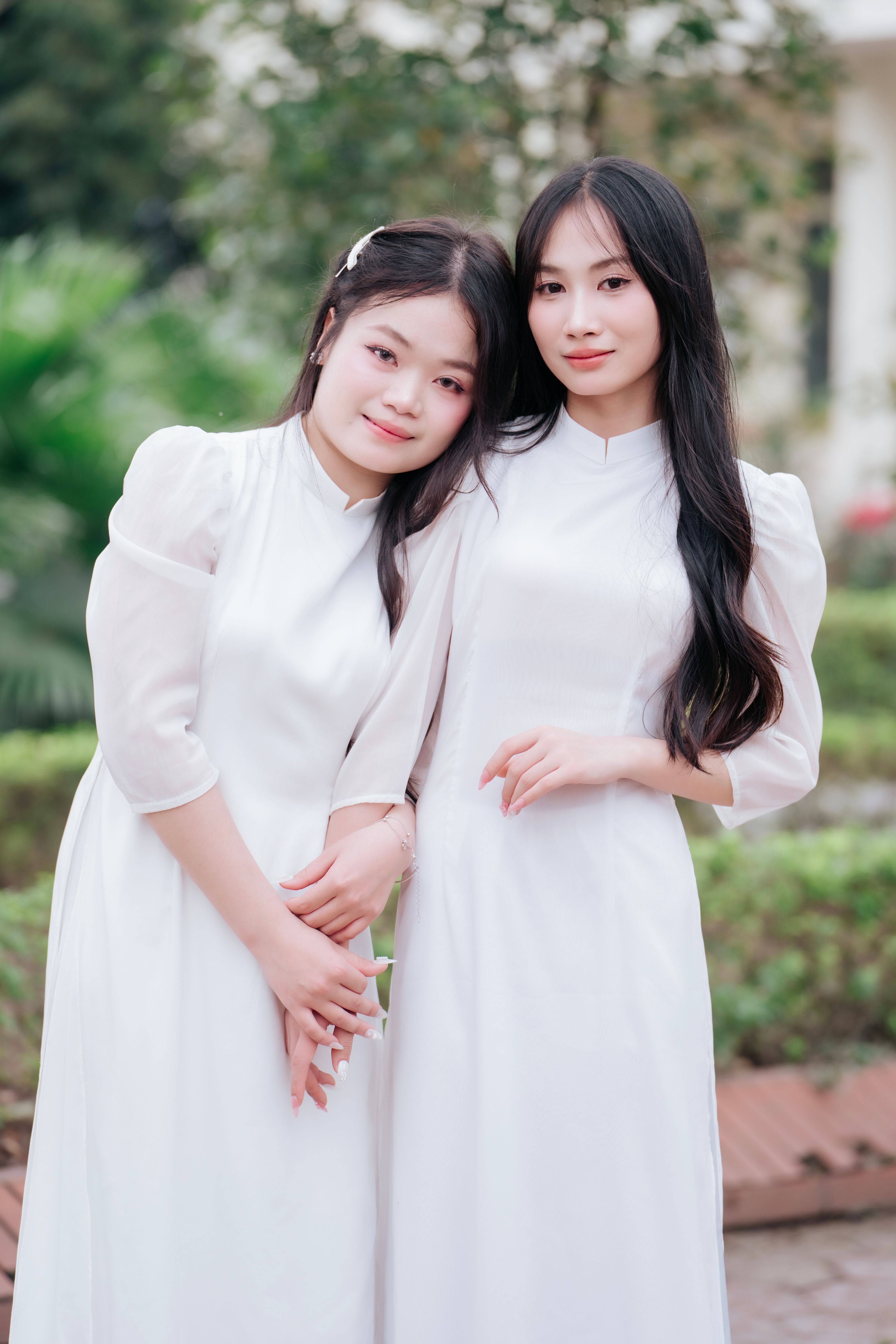 Young Asian women in maxi white dresses standing near archway  Free Stock  Photo
