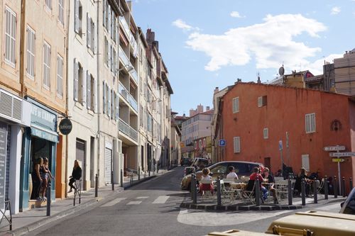 Free Charming Marseille street with cafés and pedestrians under a bright summer sky. Stock Photo