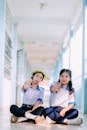 Two Students Sitting in School Corridor