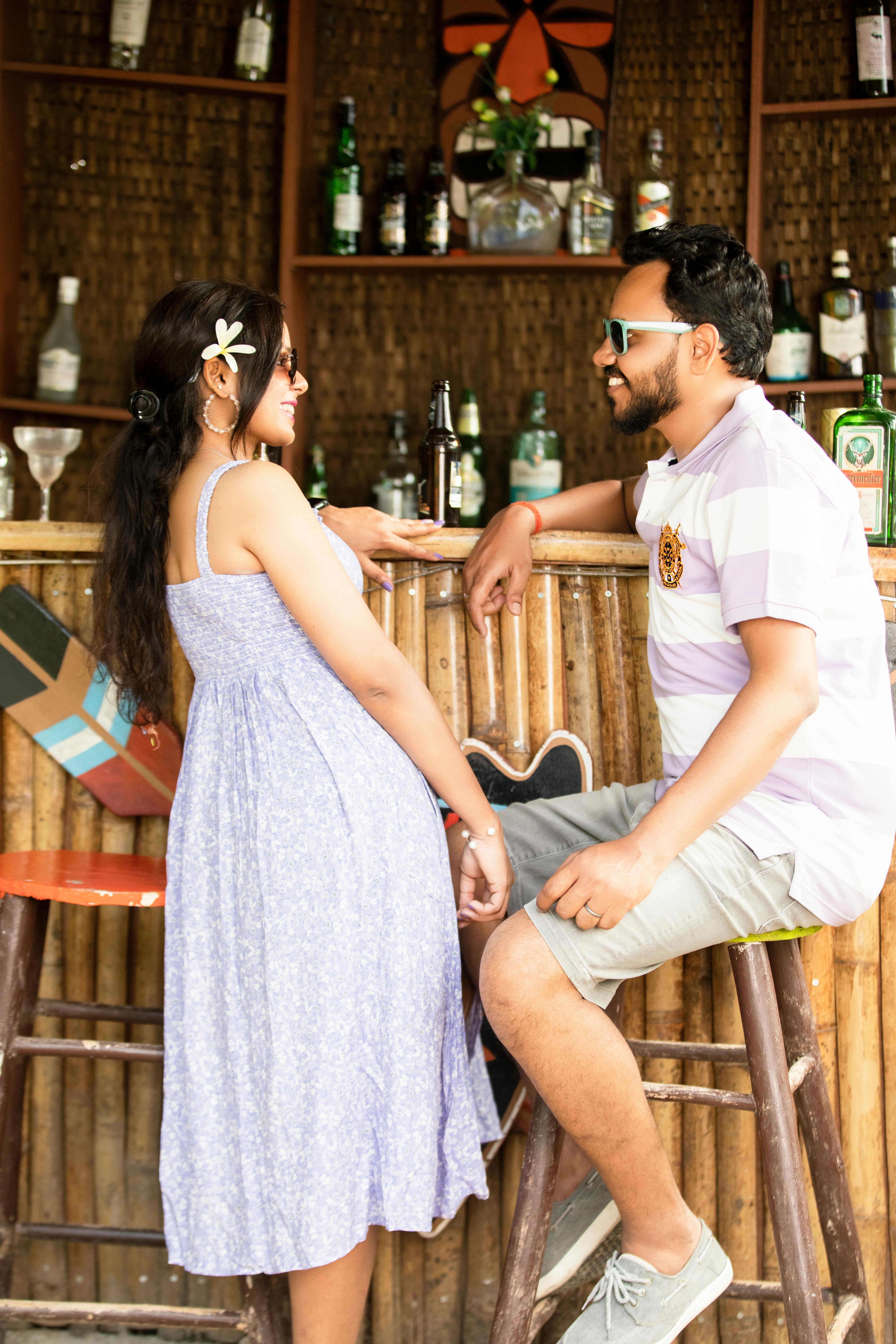 Free A cheerful couple relaxing at a bamboo-themed bar in warm daylight, capturing a casual, tropical vibe. Stock Photo