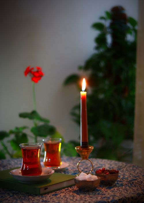 Free Warm indoor scene with tea glasses, candlelight, and floral decor, perfect for relaxation. Stock Photo