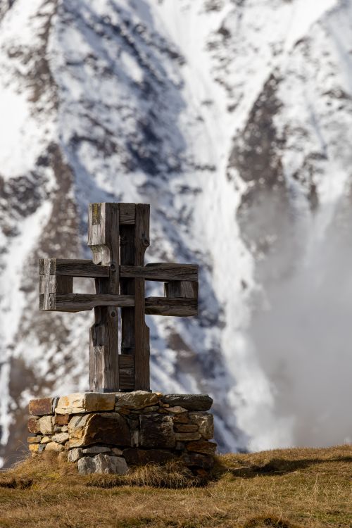 Free Majestic wooden cross set against a snowy mountain backdrop in Kärnten, Austria. Stock Photo