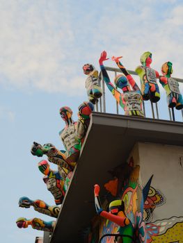 Colorful artistic sculptures on a building rooftop against a blue sky.