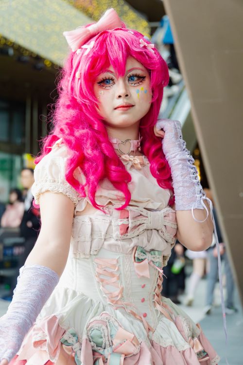 Free Colorful cosplayer wearing pink wig and detailed dress at convention, showcasing anime style. Stock Photo