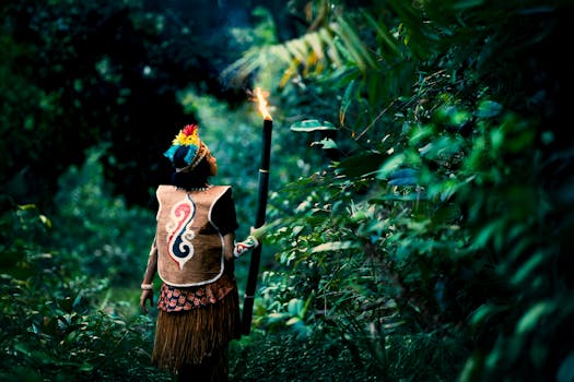 A person in traditional attire holding a torch in a Papua jungle, Jayapura, Indonesia.