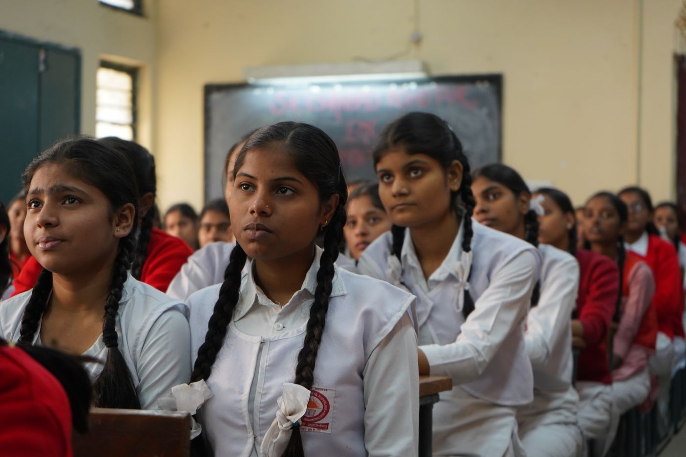 Schoolgirls in uniform listening attentively during a classroom lesson