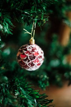 Close-up of a red bauble with snowy design hanging on a Christmas tree.