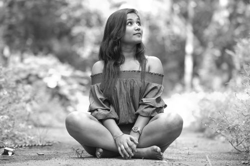 Free A young woman sits cross-legged in a natural setting, looking serenely upward. Stock Photo