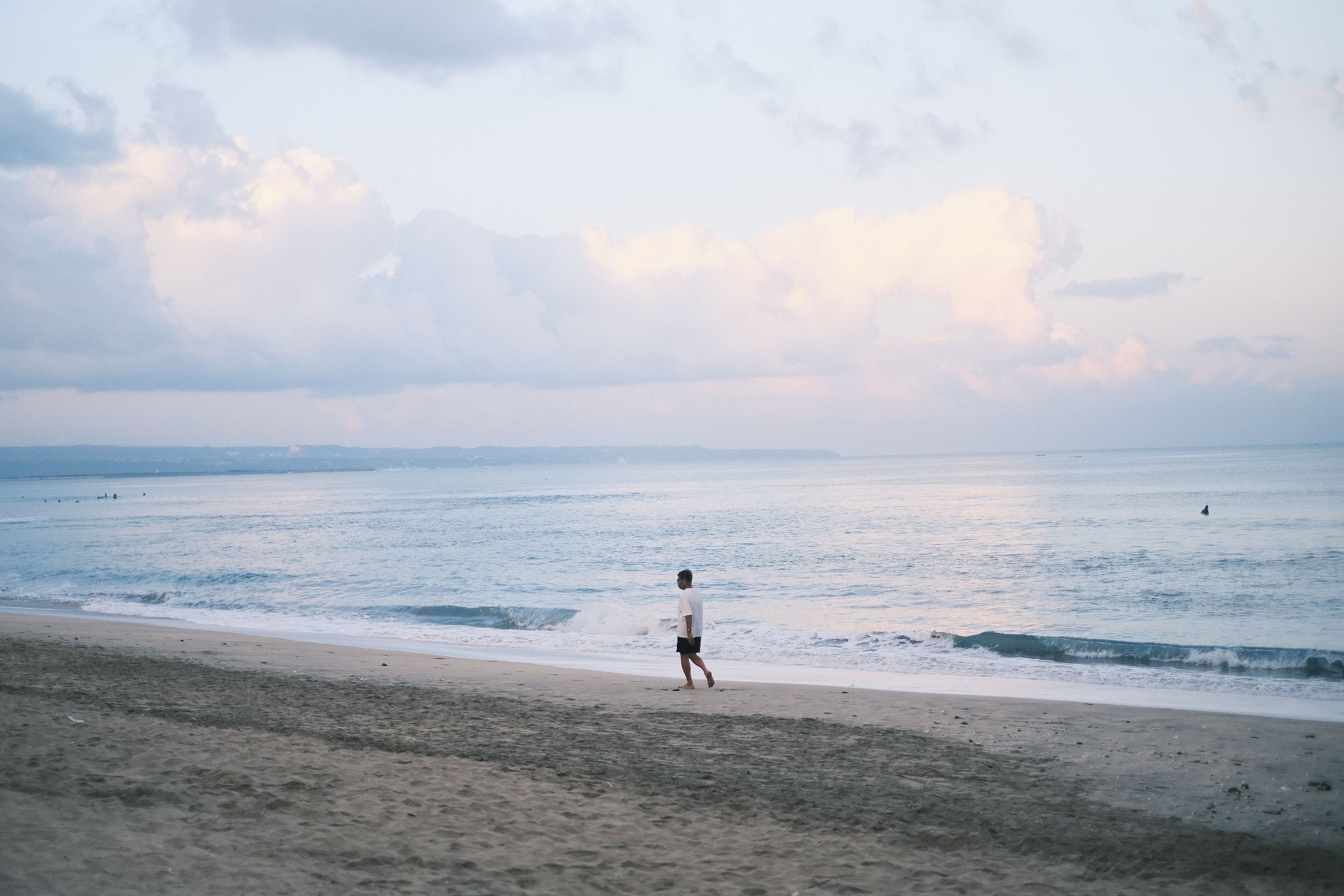 Solitary walk on a tranquil Bali beach at sunset, capturing serenity and natural beauty.