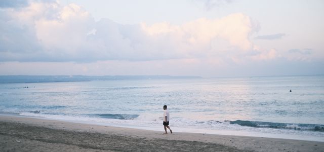 Solitary walk on a tranquil Bali beach at sunset, capturing serenity and natural beauty.