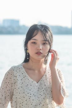 Serene portrait of a young woman by the waterfront in soft daylight.