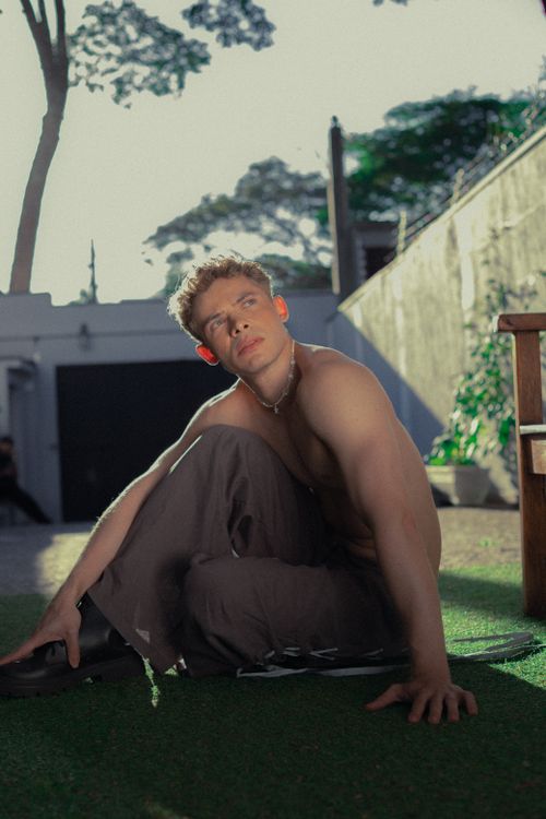 Free A thoughtful young man sitting in São Paulo garden, illuminated by the soft sunlight. Stock Photo
