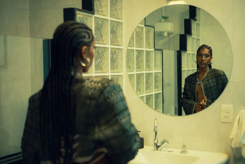 woman showing natural afro braids in salon mirror