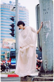 Stylish woman in flowing dress poses against a city backdrop.