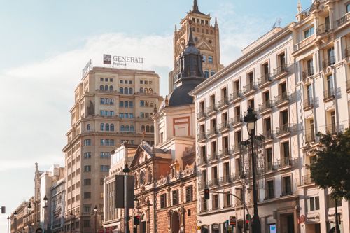 Free A sunny street scene in Madrid showcasing historic architecture and modern buildings. Stock Photo