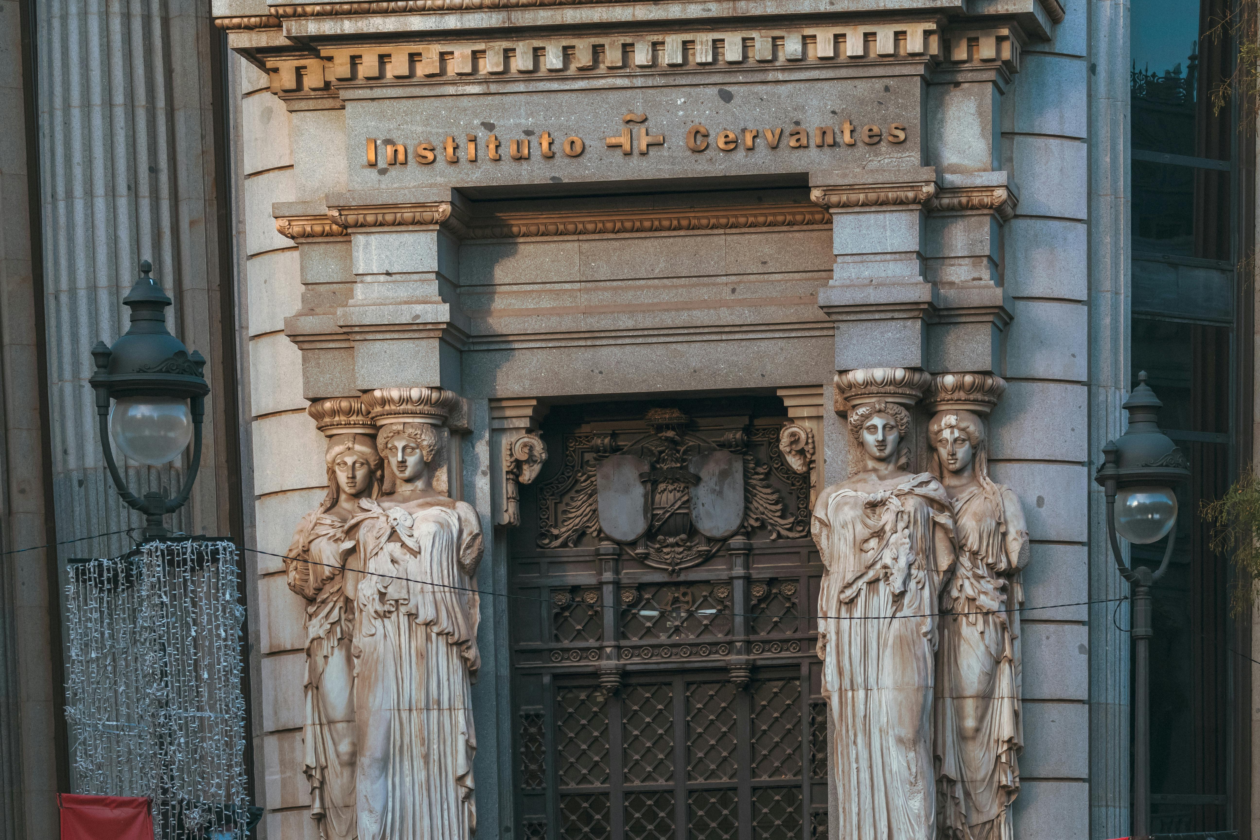 Front view of Instituto Cervantes entrance with classical sculptures in Madrid.