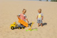 Children Playing with Toy Trucks on Sandy Beach