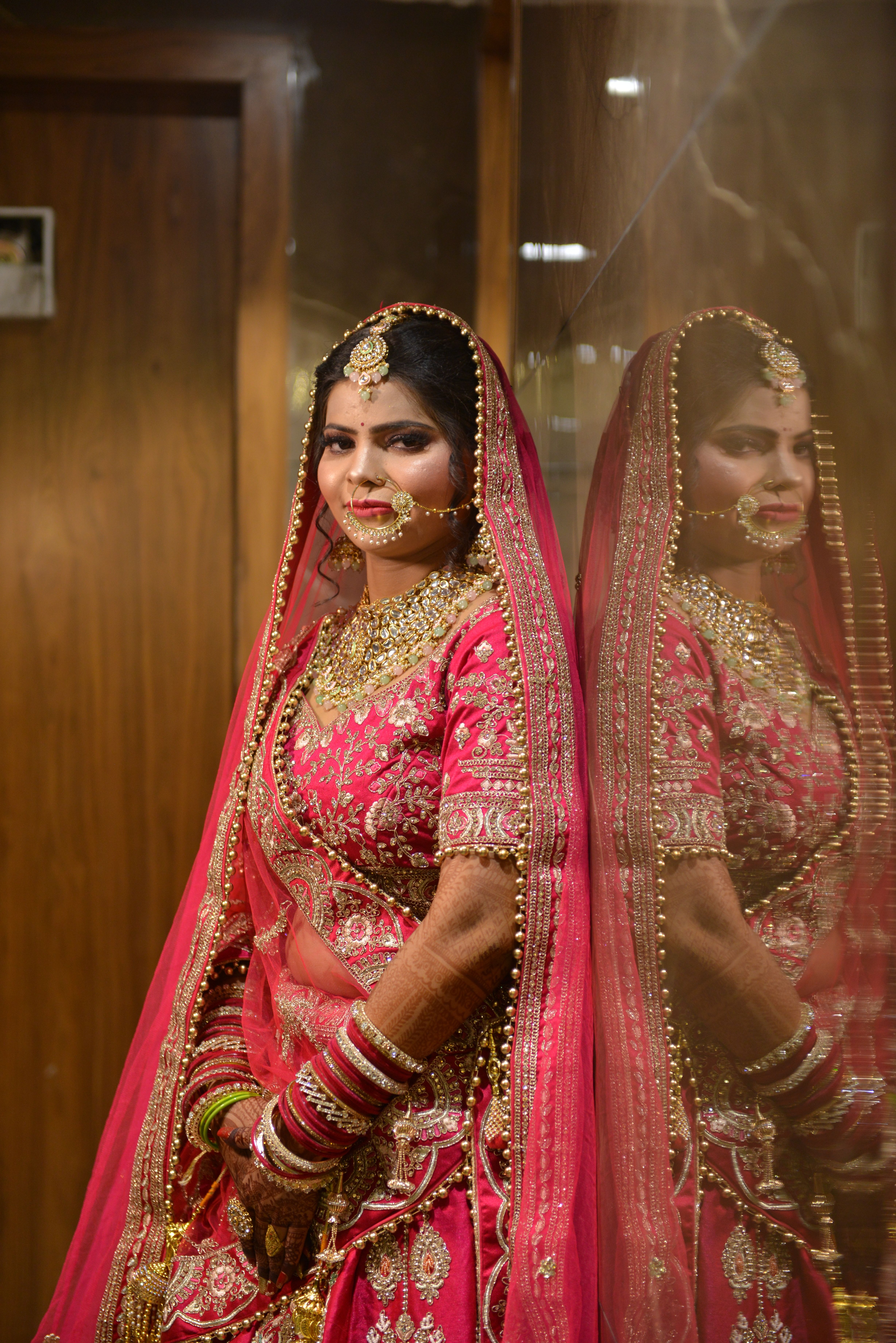 Beautiful Indian bride in vibrant pink traditional wedding dress with golden embroidery.