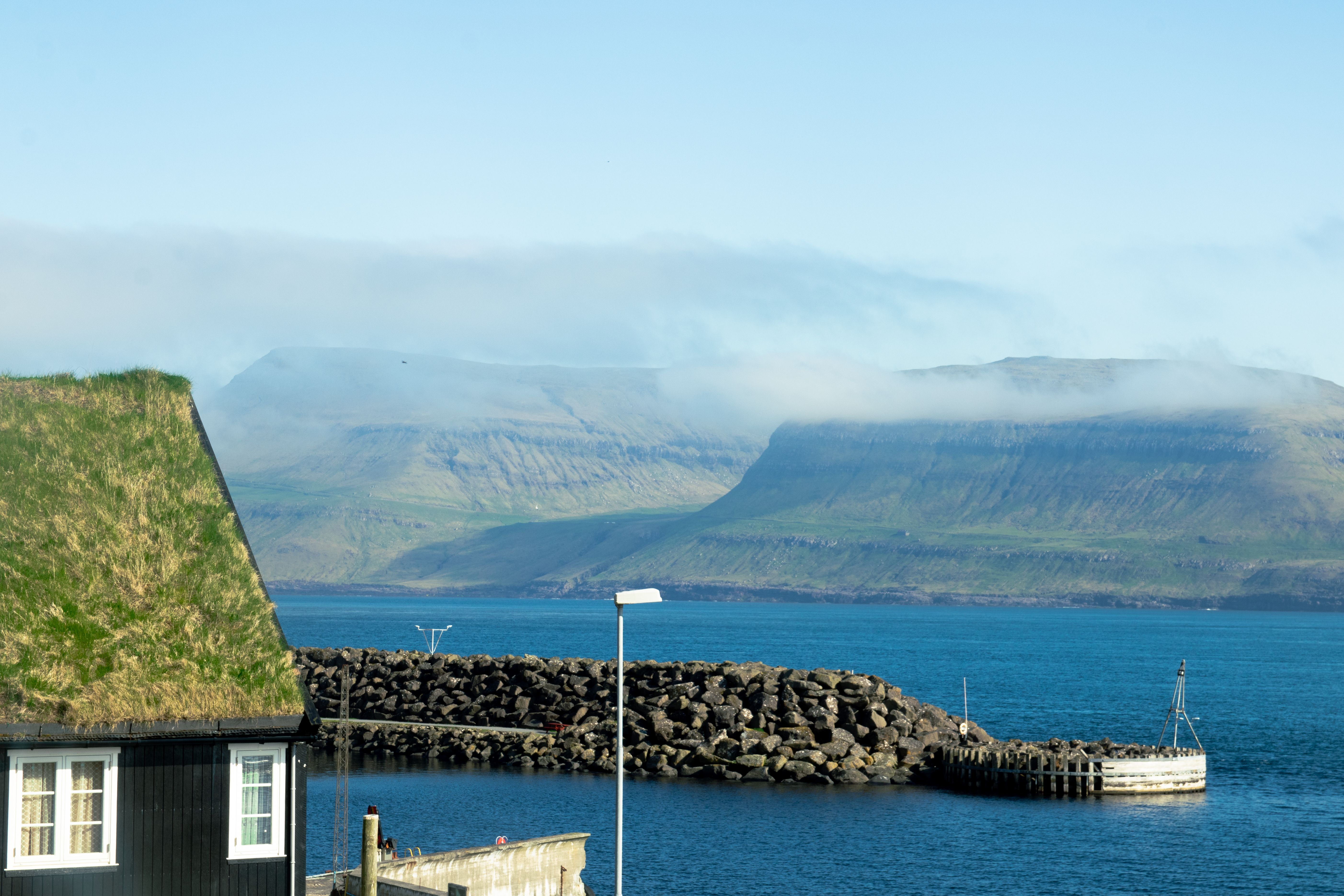 Explore the serene beauty of the Faroe Islands with misty mountains and blue ocean.