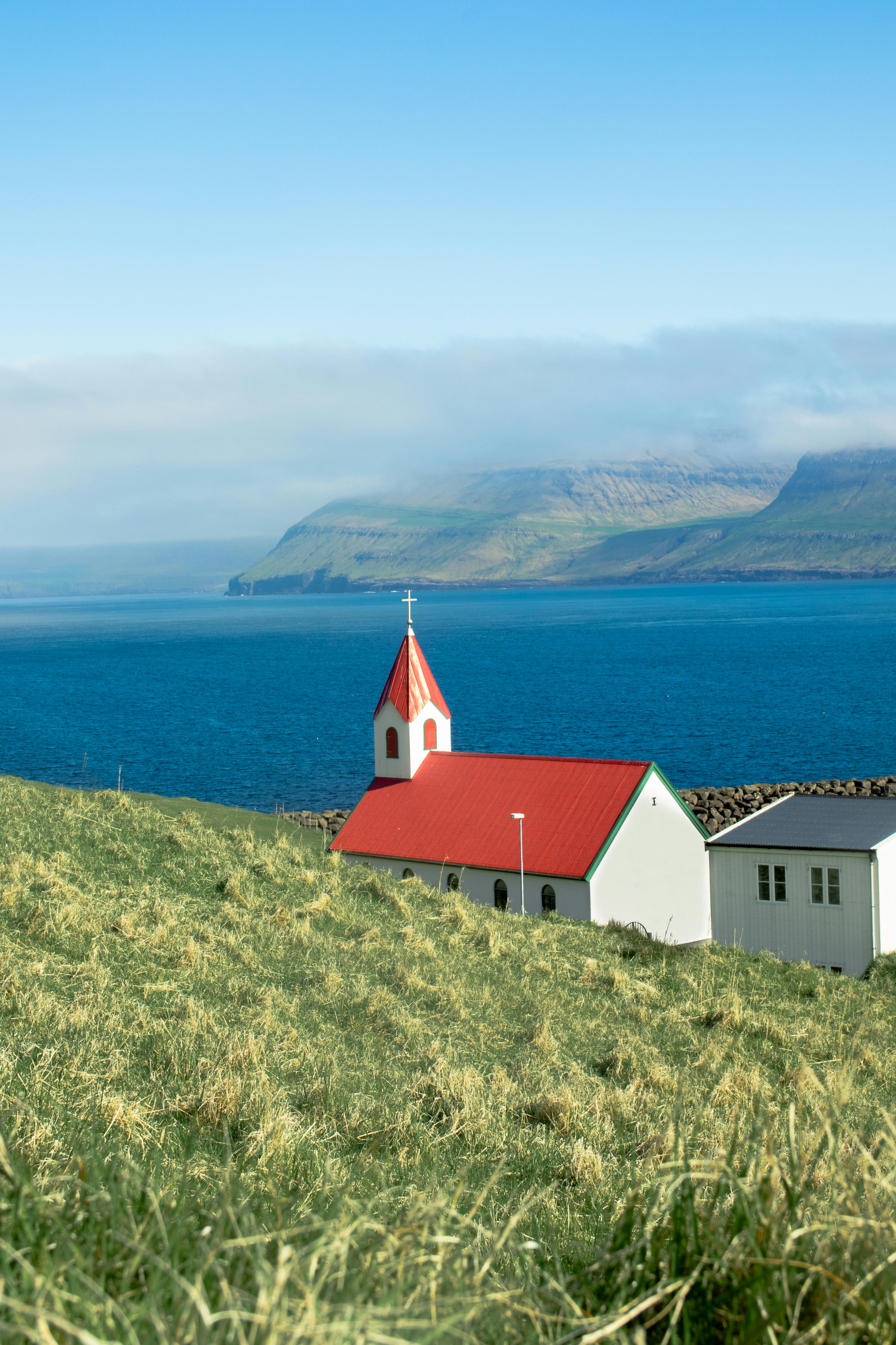 A picturesque church with a red roof by the ocean in the Faroe Islands on a clear day.