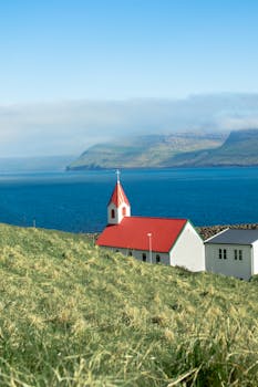 A picturesque church with a red roof by the ocean in the Faroe Islands on a clear day.