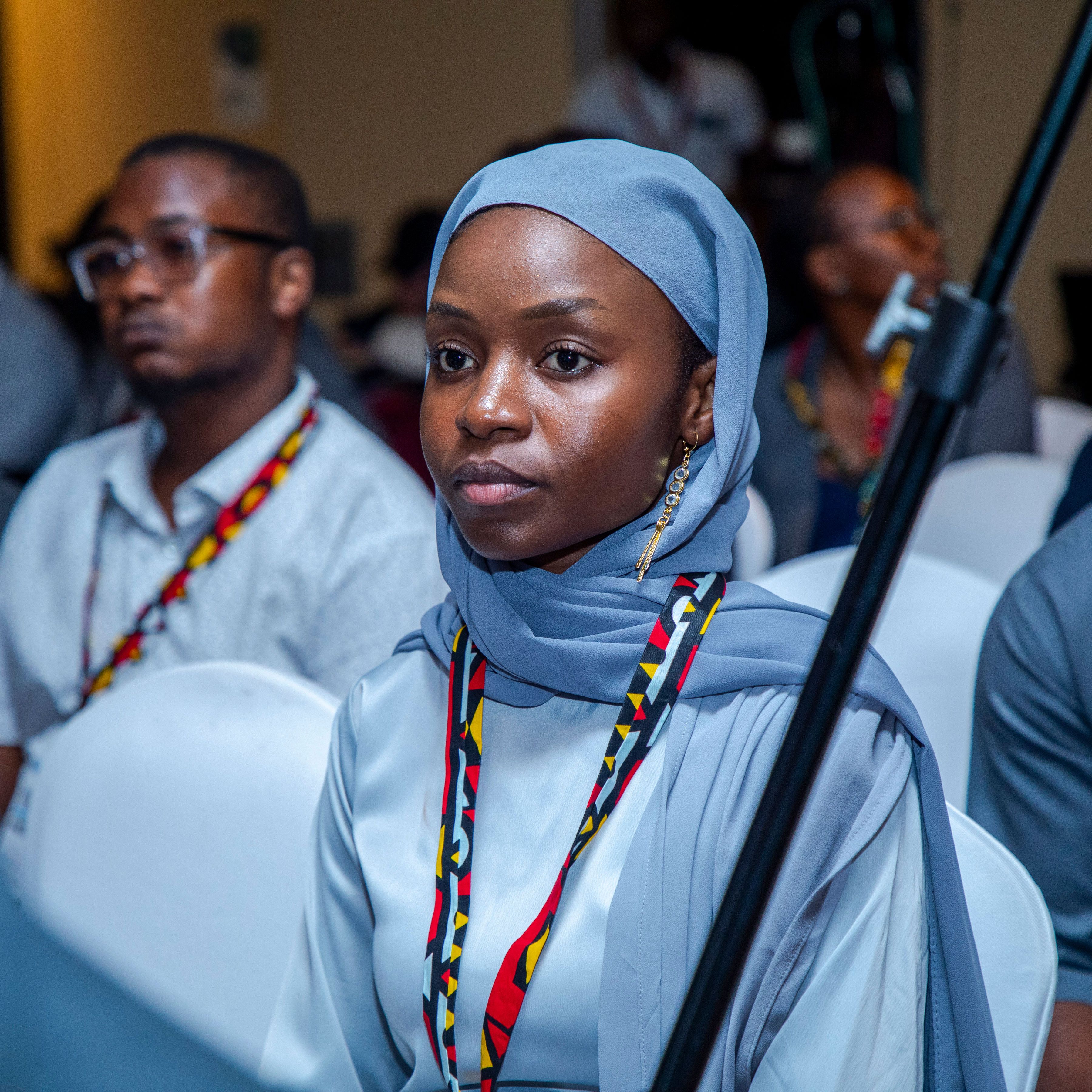 Focused woman in a hijab attentively participating at a conference session indoors.