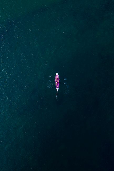 Drone shot of a single boat in deep blue water, showcasing solitude and vastness.
