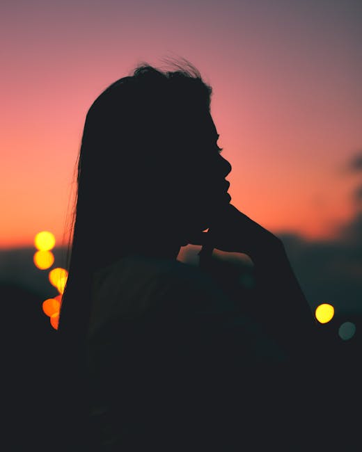 Captivating silhouette of a woman against a vibrant sunset sky, enhanced by bokeh lights.